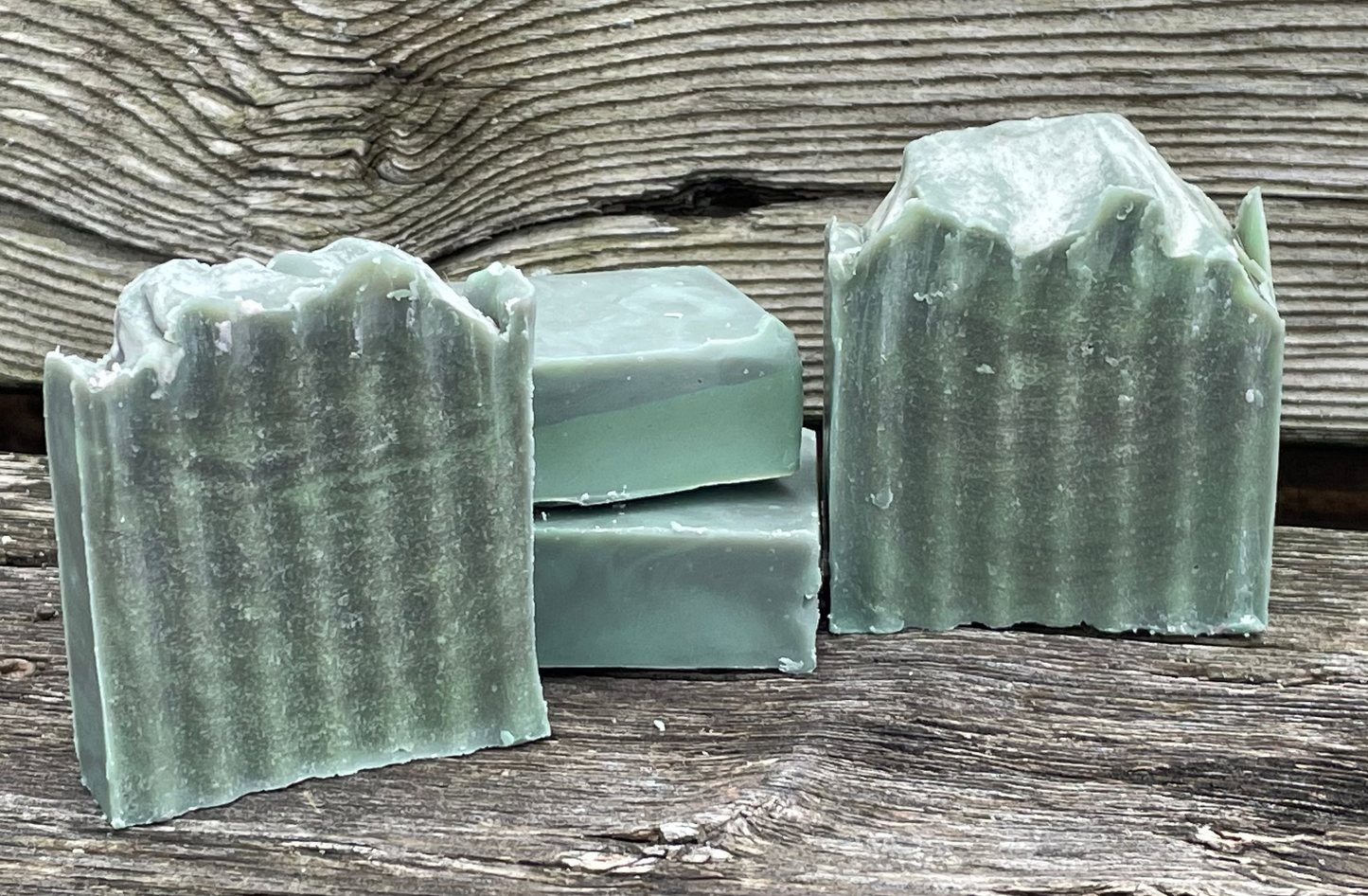 Green soap bars with a wavy texture on a wooden surface