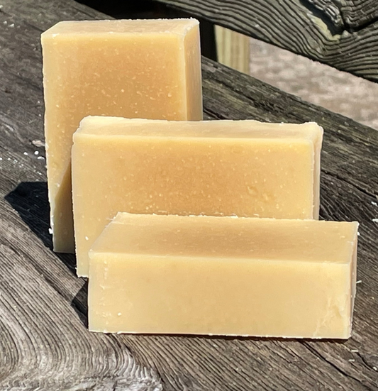 Three bars of beige soap on a wooden surface