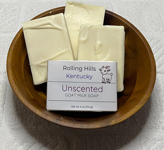 Unscented soap bars in a wooden bowl on a white surface.