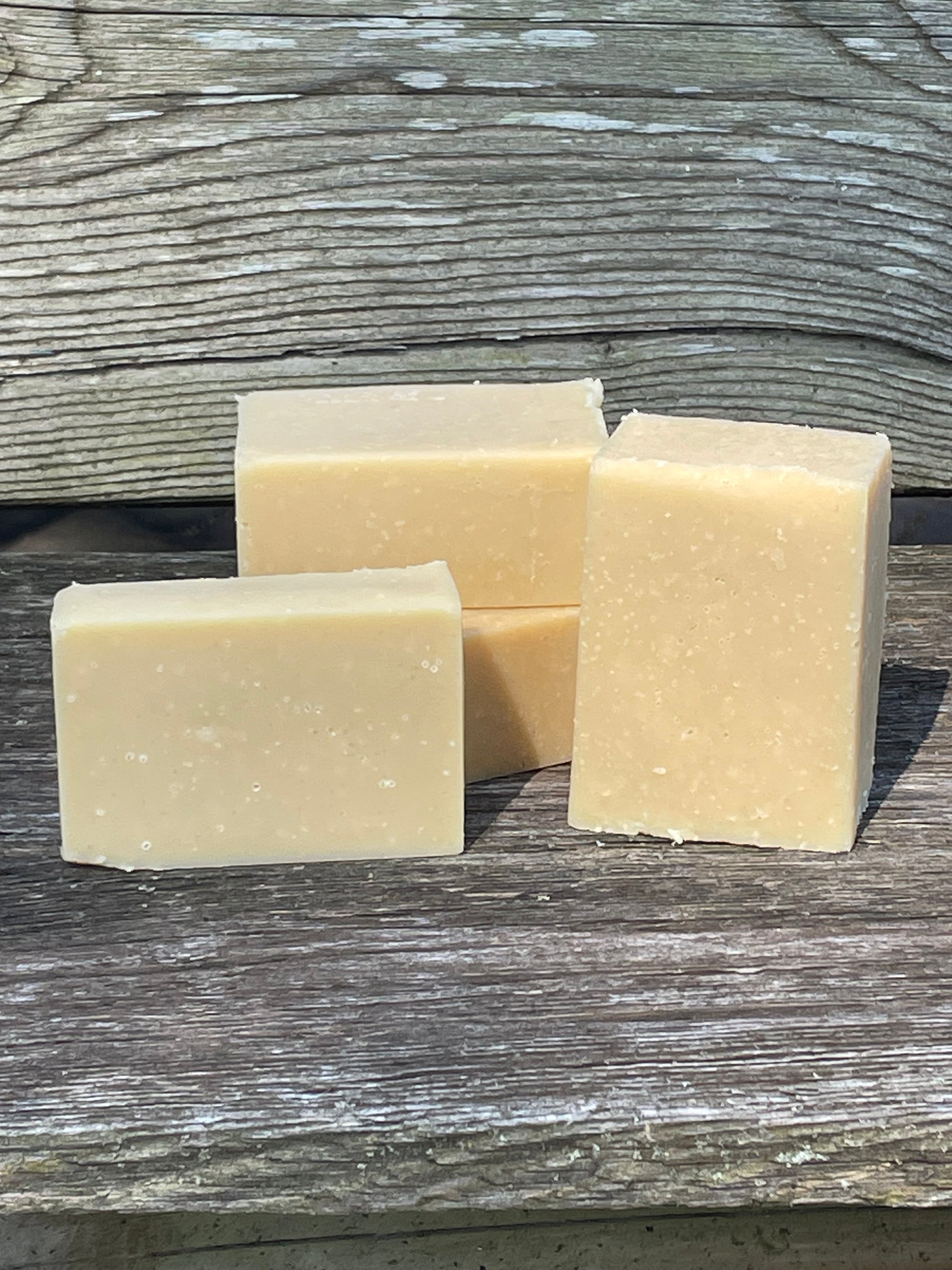 Four square bars of soap on a wooden surface