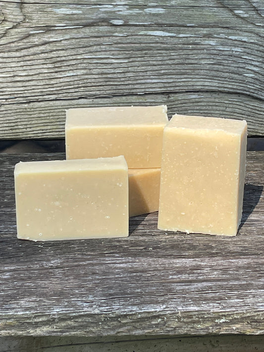 Four square bars of soap on a wooden surface
