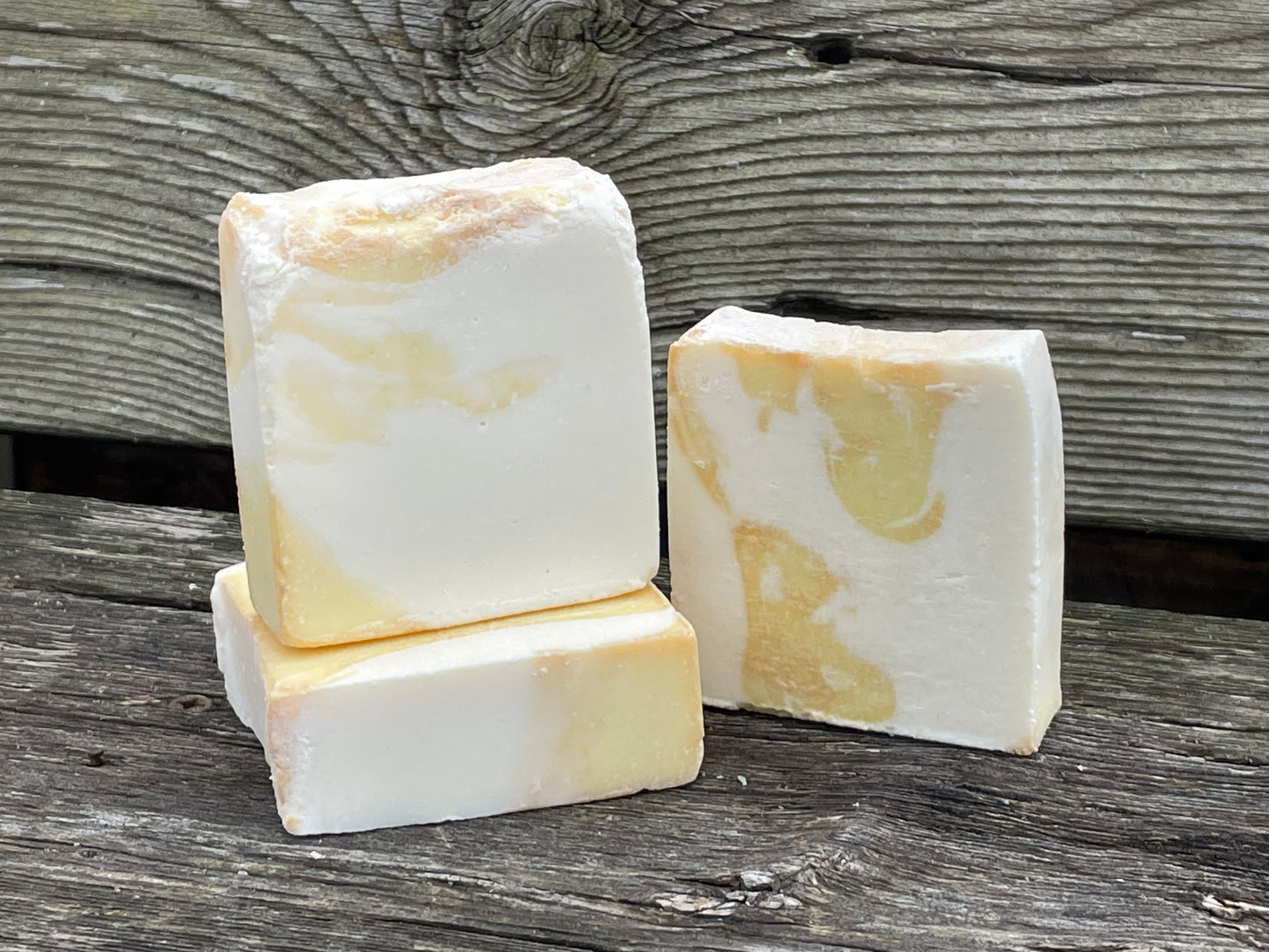 Three bars of soap with a marble pattern on a wooden surface