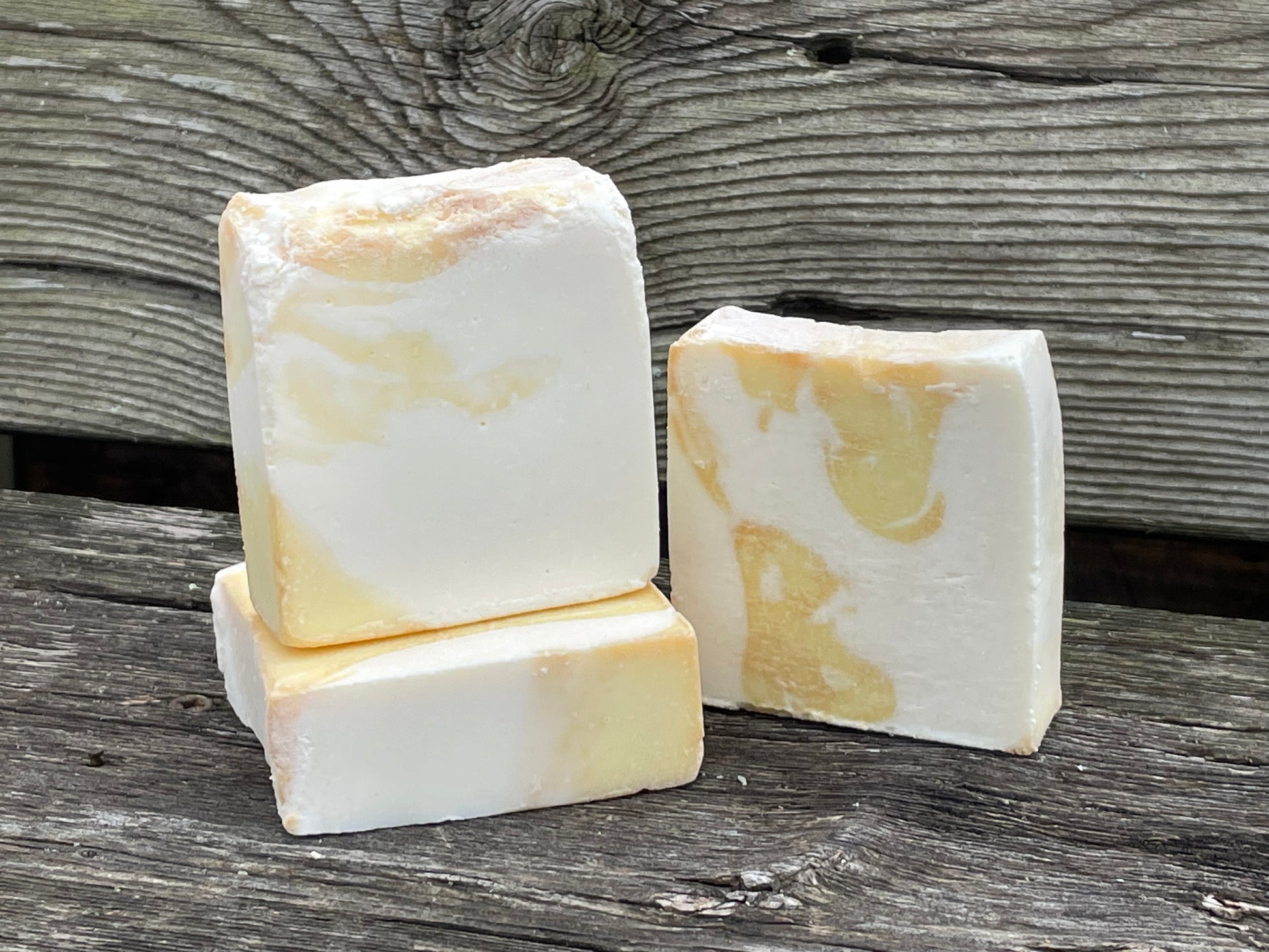 Three bars of soap with a marble pattern on a wooden surface