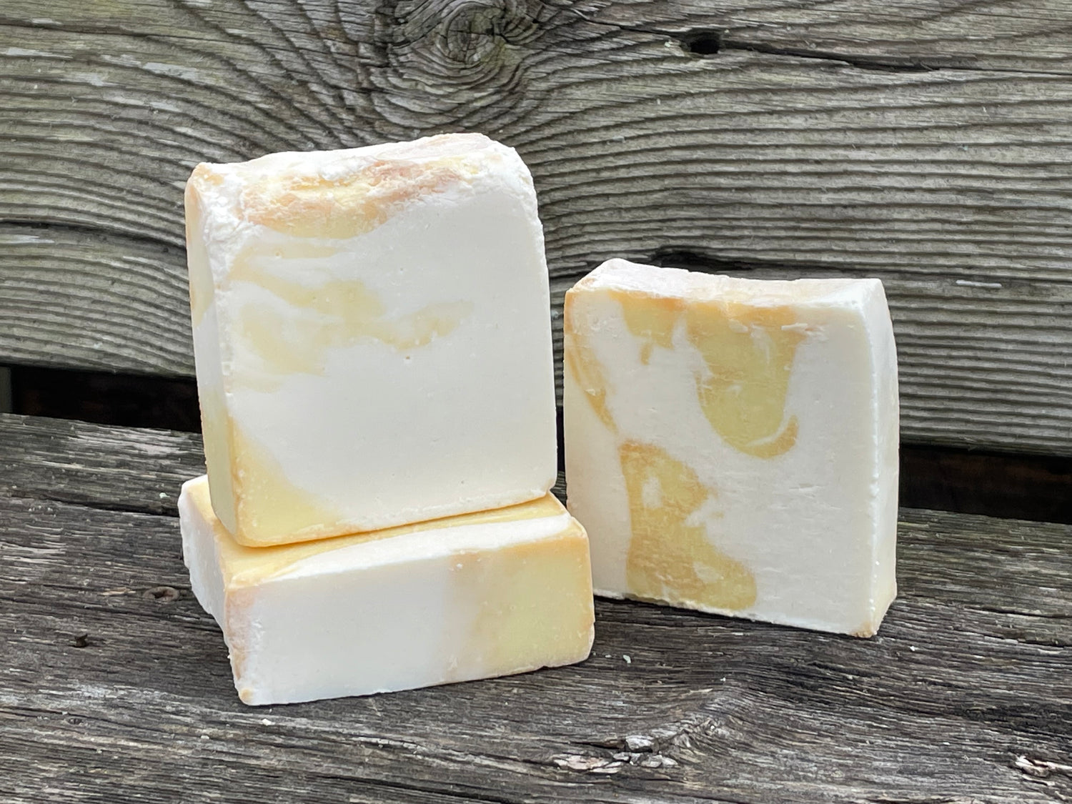 Three bars of soap with a marble pattern on a wooden surface