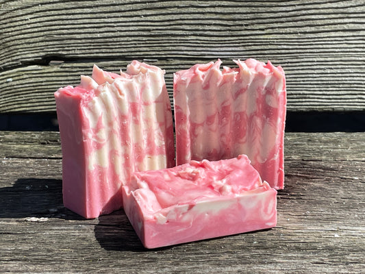 Three pink and white marbled soap bars on a wooden surface