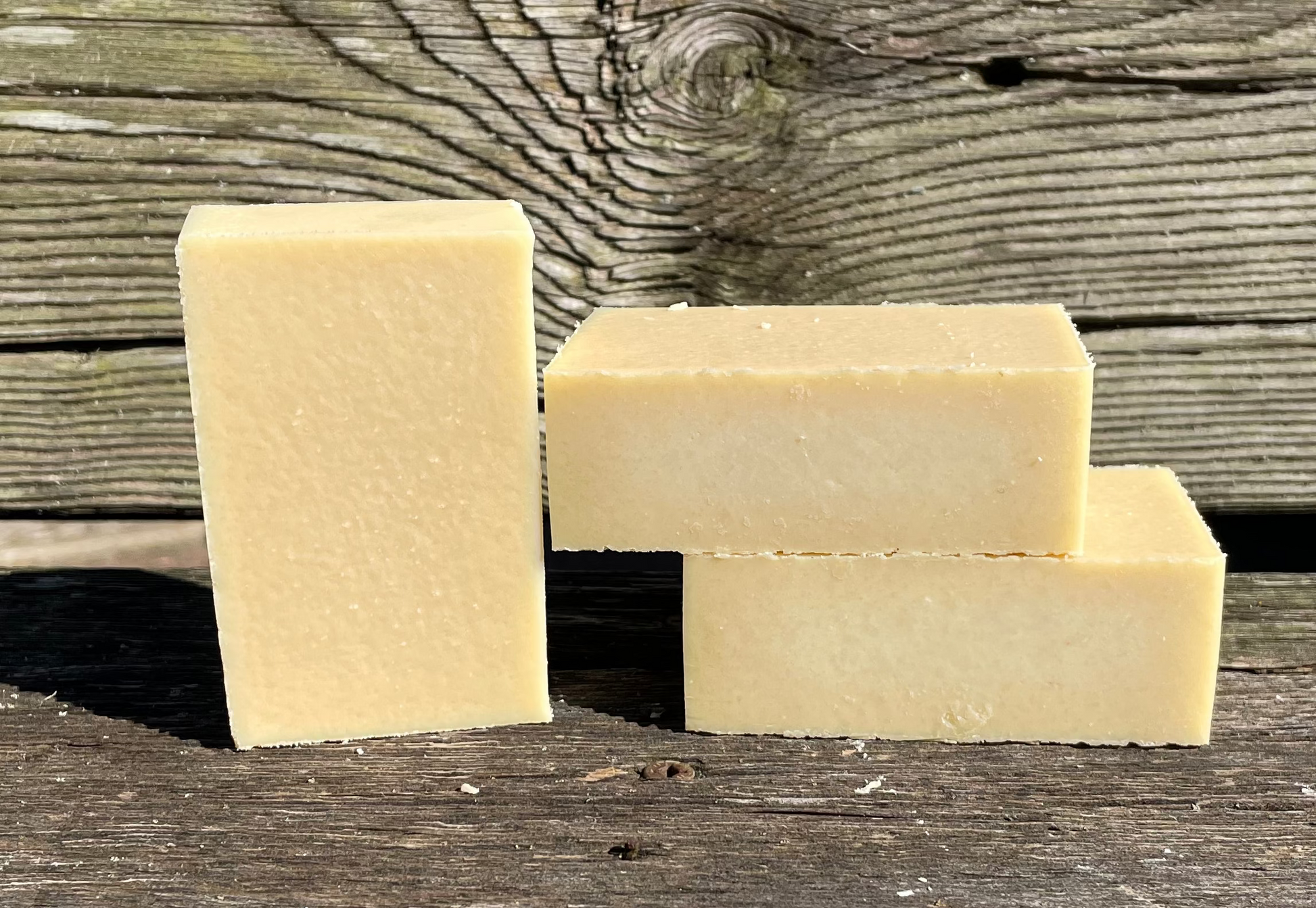 Three beige soap bars on a wooden surface